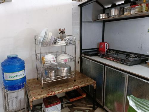 a kitchen with a stove and a shelf with dishes at Nhà nghỉ Phương Dung in Phu Quoc