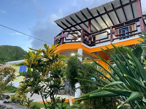 a house with a balcony with a motorcycle in front of it at Posada Ashanty in Providencia