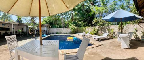 un patio con sillas, una sombrilla y una piscina en Santai Bungalow, en Gili Trawangan