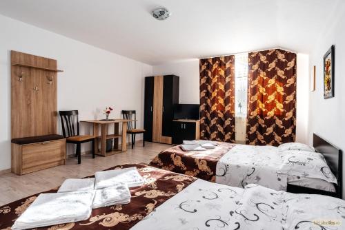 a hotel room with two beds and a table at Sweet Home Bucovina- Baza perfecta pentru explorarea Bucovinei in Frasin