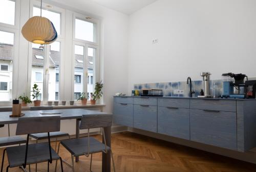 een keuken met blauwe kasten en een tafel met stoelen bij WELL Pretty Places - sustainable interior design in the Citycenter in Kassel