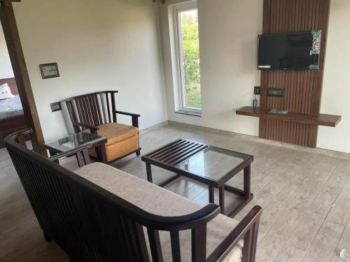 a living room with chairs and a table and a tv at vihangama Home Stay in Chāmundi