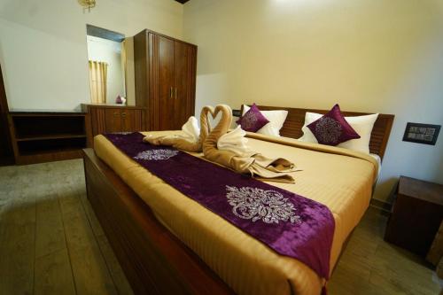 a bedroom with a large bed with purple sheets at vihangama Home Stay in Chāmundi