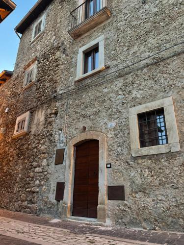 um antigo edifício de pedra com uma porta e janelas em La casa di mezzo em Calascio