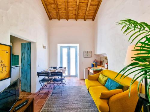 a living room with a yellow couch and a table at FLH Vale Judeu Rustic Mezzanine Cottage I in Loulé