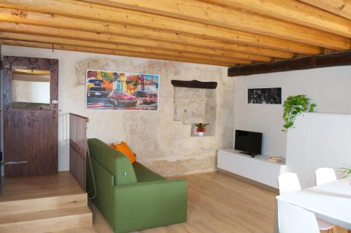 a living room with a green chair and a television at Residence Porta Della Muda in Vittorio Veneto