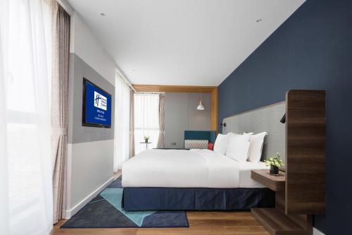 a bedroom with a large white bed and a blue wall at Holiday Inn Express Foshan Chancheng by IHG in Foshan