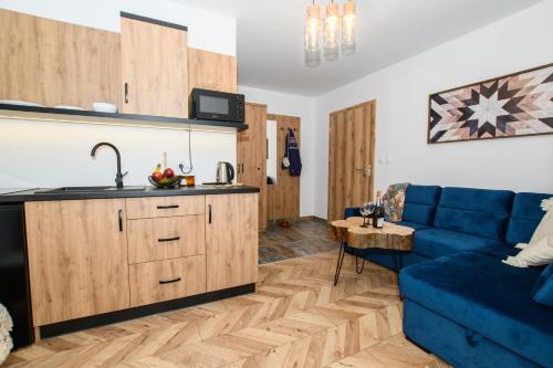 uma cozinha e uma sala de estar com um sofá azul em Maryna Bór em Zakopane
