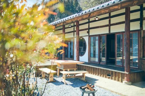 a building with a picnic table and benches in front of it at Kominkayado LOOF Kyonoie in Ōwatari