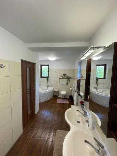 La salle de bains est pourvue de 2 lavabos et de 2 baignoires. dans l'établissement City Garden escape, à Popeşti-Leordeni