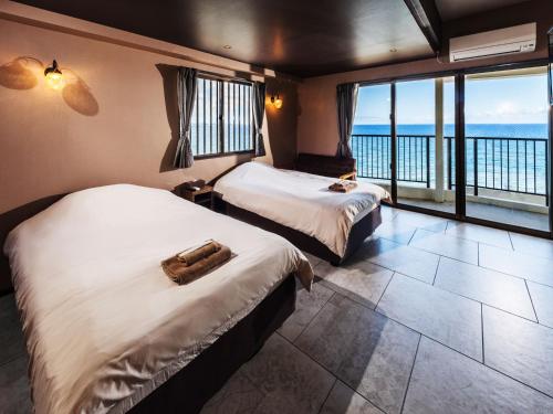 two beds in a room with a view of the ocean at Hotel Sunset American in Chatan
