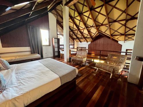 a bedroom with a bed and two chairs and a table at Sandy Feet Siargao in General Luna
