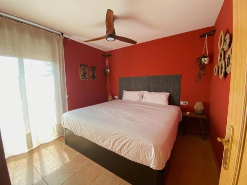 1 dormitorio rojo con 1 cama y ventilador de techo en Casita Mae: chill and enjoy in Majanicho. en La Oliva