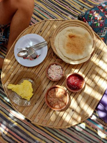 una mesa de madera cubierta con platos y tazones de comida en Forest Camp Siwa - كامب الغابة, en Siwa