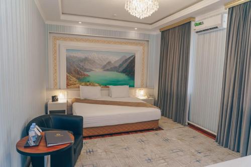 una camera d'albergo con letto, tavolo e sedia di Asmald Palace Hotel a Qo‘qon