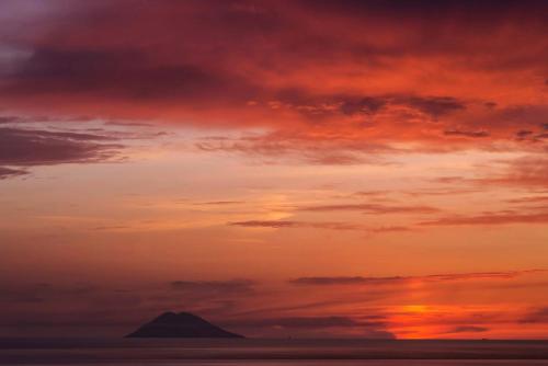 a sunset over the ocean with a mountain in the distance at Solmaris Tropea Rooms & Suites in Tropea