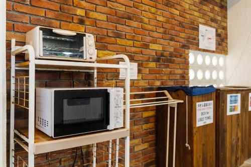 a microwave on a rack next to a brick wall at Hotel Sunset American in Chatan