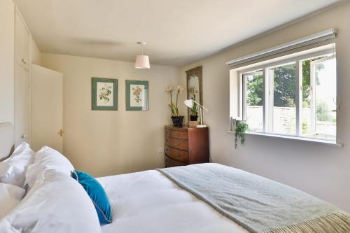 a bedroom with a white bed and a window at The Butlers Bungalow Beverston Castle in Tetbury