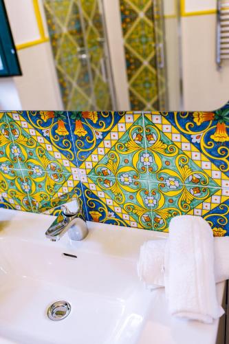 a bathroom sink with a yellow and blue patterned umbrella at Vallone dei Mulini Suite in Sorrento