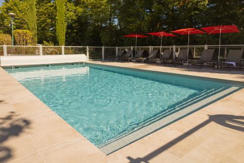 a swimming pool with chairs and red umbrellas at ibis Lyon Nord in Dardilly