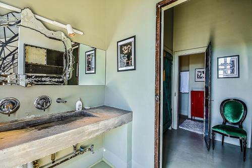La salle de bains est pourvue d'un miroir et d'une chaise verte. dans l'établissement Badacsony Loft, à Bytom