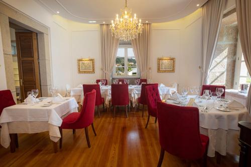 a restaurant with white tables and red chairs and a chandelier at Solar do Requeijo by Luna Hotels & Resorts in Arcos de Valdevez