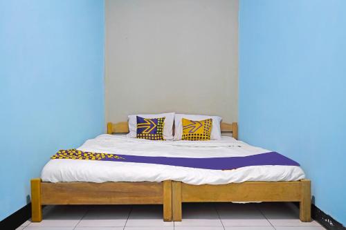 Cama en habitación con pared azul en SPOT ON 91543 Pondok Denki 11, en Bandung