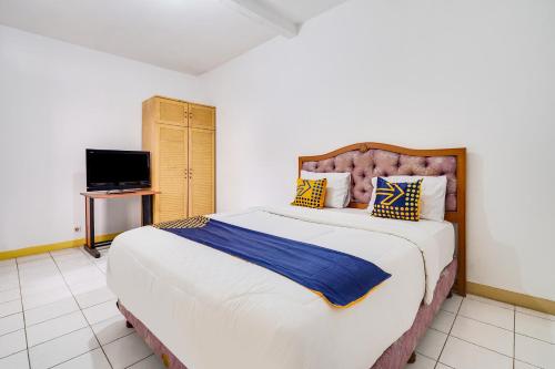 um quarto com uma cama grande e uma televisão em OYO 91546 Dewi Sudirman Homestay em Bandung