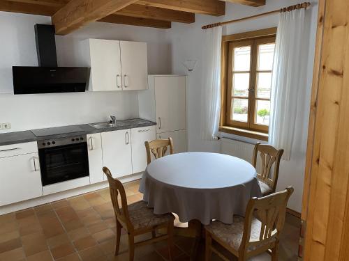 a kitchen with a white table and chairs and a window at Gästehaus Winzerhof Bader in Heuchelheim-Klingen