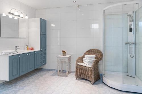 uma casa de banho com um chuveiro, uma cadeira e um lavatório. em Moens Motell em Fiskå