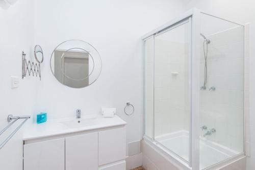 a white bathroom with a shower and a sink at Close to Coast in Forster