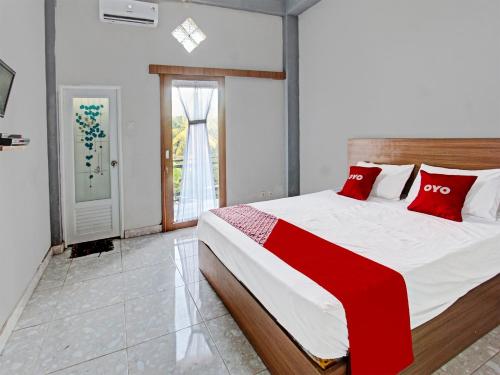 a bedroom with a large bed with red pillows at OYO 91210 Hotel J3 in Lombok