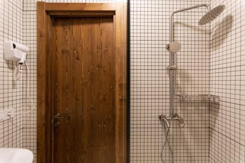 a wooden door in a bathroom with a shower at Porto Gumati in Kutaisi