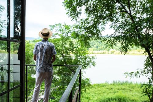 a man standing on a balcony looking out at a lake at Porto Gumati in Kutaisi