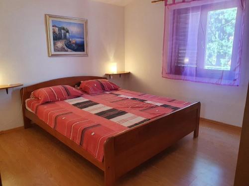 Un dormitorio con una cama con sábanas rojas y una ventana en Apartmani Ruk en Vrbanj