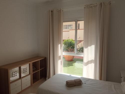 ein Schlafzimmer mit einem Bett und einem großen Fenster in der Unterkunft Golf del Sur-1 bedroom poolside apartment-sleeps 4 in San Miguel de Abona
