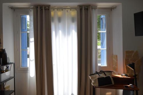 two windows with white curtains in a room at AUX 4 LOGIS Appart-hotel - Studio Le City - Petit déjeuner inclus 1ère nuit in Foix