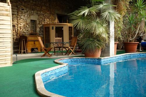 - une piscine dans une cour avec des palmiers dans l'établissement Les Cornadis, à Saint-Priest-sous-Aixe