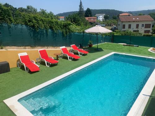 - une piscine avec des chaises longues et un parasol dans l'établissement Casa de piedra, A Lameira, à A Coruña