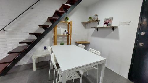 uma mesa branca e cadeiras num quarto com escadas em Inspired Homes, Empire Duplex#2, 6pax em Petaling Jaya
