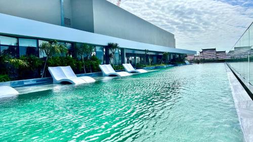 a swimming pool with white chairs in front of a building at The Song Luxury Condotel Vung Tau - Căn hộ cao cấp Luca's House in Vung Tau