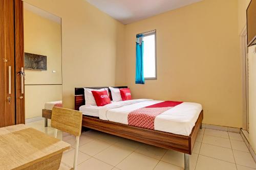 Un dormitorio con una cama con almohadas rojas y una ventana en OYO 91532 Malioboro Guesthouse, en Yogyakarta