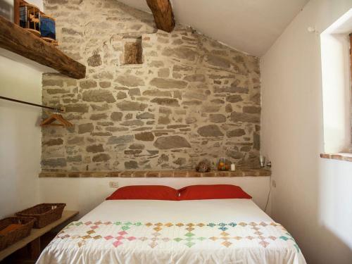 a bed in a room with a stone wall at Il Tamantino in Gubbio