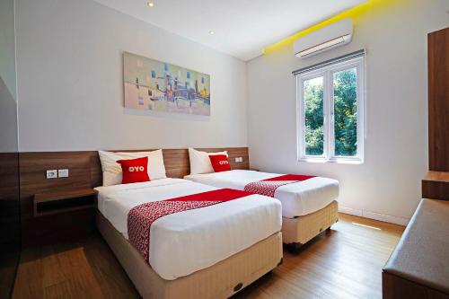 1 dormitorio con 2 camas y ventana en Super OYO Collection O 91472 The Regia Dago en Bandung