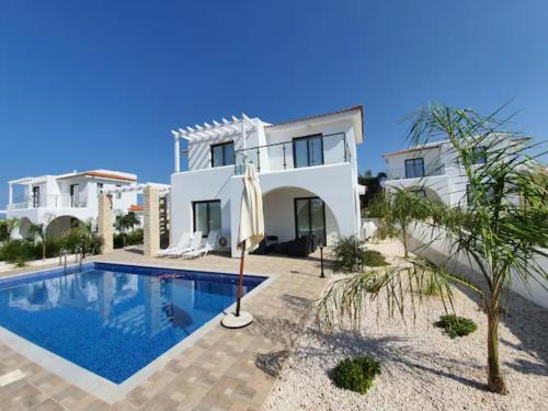 a villa with a swimming pool in front of a house at St. Georgiana Villa 7 in Peyia
