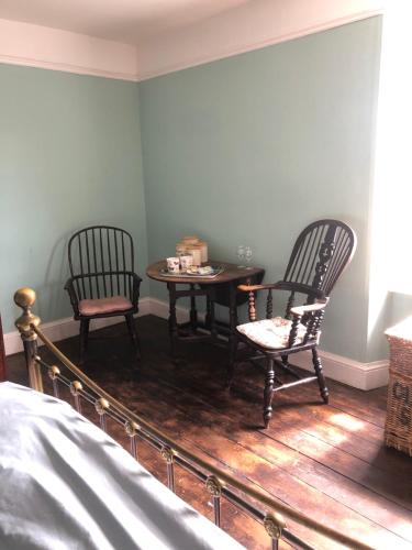 The Victorian House في بريدبورت: غرفة نوم بها كرسيين وطاولة وسرير