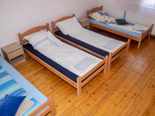 two beds in a room with wooden floors at Prenoćište Vanja in Padej