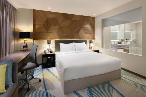 um quarto com uma grande cama branca, uma secretária e uma cadeira. em Holiday Inn Cebu City, an IHG Hotel em Cebu