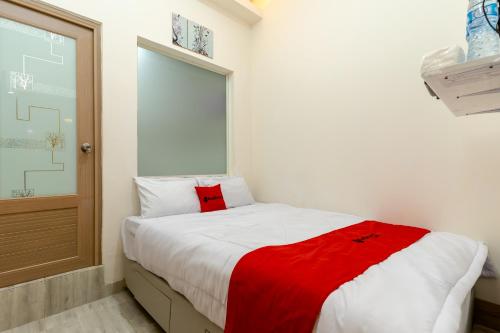 a bedroom with a bed with a red blanket on it at RedDoorz Plus Near RS Royal Taruma Grogol in Jakarta