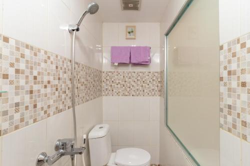 a bathroom with a toilet and a shower with purple towels at RedDoorz Plus Near RS Royal Taruma Grogol in Jakarta